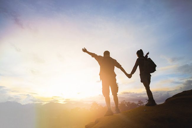 two hikers holding hands